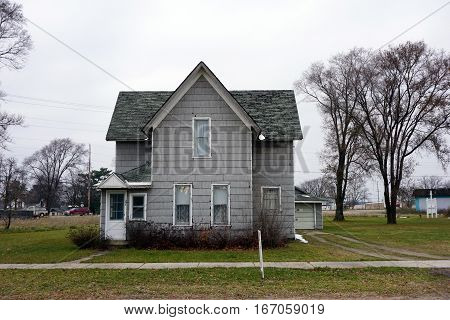 MANCELONA, MICHIGAN / UNITED STATES - NOVEMBER 27, 2016:  An old two-story gray home stands near downtown Mancelona.