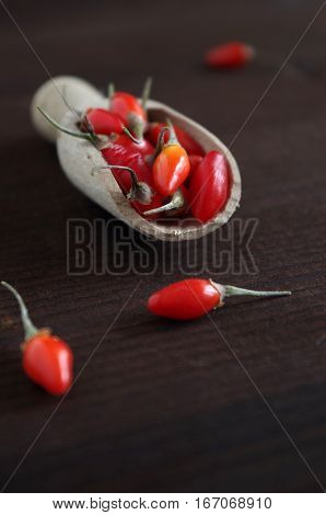 fresh healthy goji berries in front of a brown wooden background