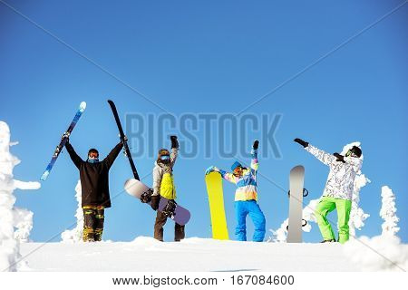 Group of happy friends snowboarders and skiers on blue sky backdrop. Ski and snowboard concept