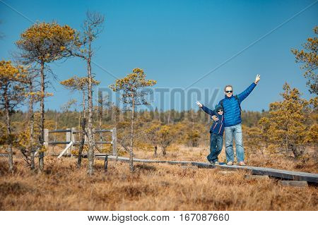 Cute little boy with his father walking on trail in swamp and having fun, Kemeri national park, Latvia