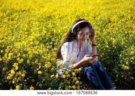 Asian hipster cute teen girl with backpack listening to the music with headphones lying on peak. Tourist traveler on background valley landscape view mock-up sunlight in trip in basque country