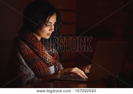 young beautiful woman in the dark typing on a laptop