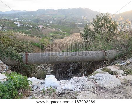 Concrete Irrigation Pipe across small garbage filled gorge in Andalusia Countryside
