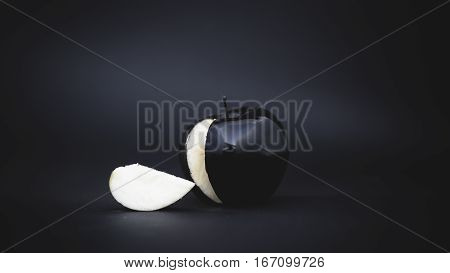 sliced black apple on a black background with a slice