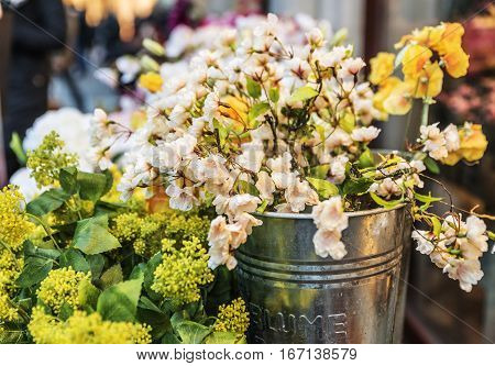 Yellowish white flowers in an iron bucket with an inscription in German 