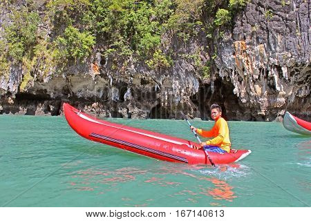 KO TAPU, THAILAND - DECEMBER 09, 2013: Man in an inflatable canoe  near Ko Tapu island in Thailand, known as James Bond Island