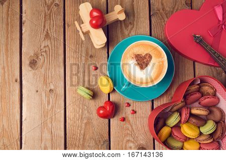 Valentines day concept with macarons coffee cup and toy airplane over wooden background. Top view from above