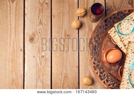 Passover concept with matzah seder plate and wine on wooden background. View from above