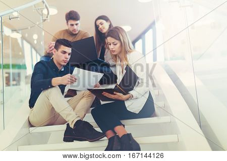 Happy group of friends sitting on the stairs in the school or college
