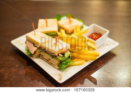 Mini sandwiches with fries and sauce on a white plate