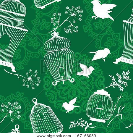 Seamless pattern with decorative white Silhouettes of bird cage flying birds plants on green background with mandala ornaments.