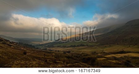 Landscape in Brecon Beacons looking towards Libanus. Valley by Pen y Fan mountain in National Park in Wales with broken sunlight highlighting village and hillside
