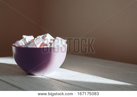 Marshmellow a purple wooden bowl on a white background. Top view. The concept of food.