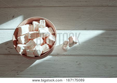 Marshmellow a wooden bowl on a white background. Top view. The concept of food.