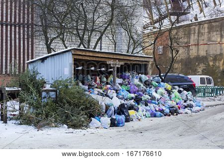 Metal hangar and garbage cans covered of large heap garbage on city street