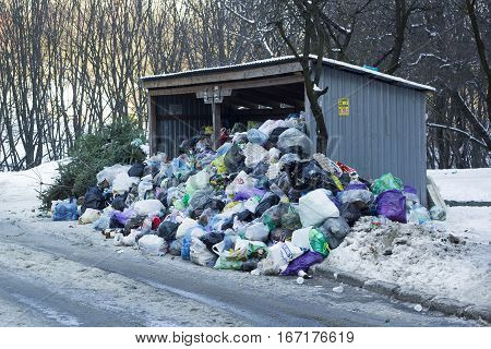 Metal hangar and garbage cans covered of large heap garbage on city street