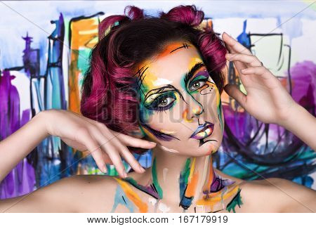 close-up fashion faceart portrait of young girl with art painting posing. Amazing creative picture with surrealistic face. Painted background