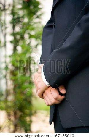 A man with folded hands stands at ceremony