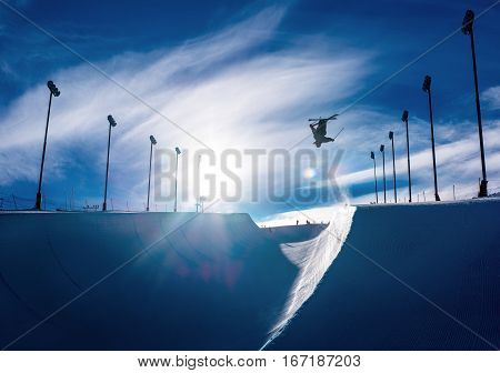 Skier doing an inverted trick in a winter snow halfpipe