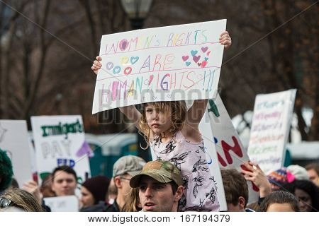 ATLANTA, GA - JANUARY 2017: A girl sitting on her father's shoulders carries a sign promoting women's rights as thousands participate in the Atlanta march for social justice and women the day after President Trump's inauguration in Atlanta, GA on January 