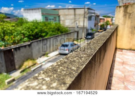 The moldy wall and blurry street with cars and houses in Bangu neighborhood, where the prison, the Penitentiary Complex of Gericino and Bangu dump are located, the West Zone of Rio de Janeiro, Brazil