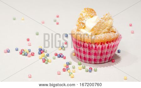 Cupcake fairy cake in red and pink paper cup with colourful colorful decorations on white background