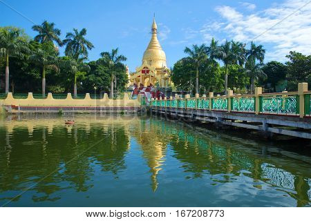 Buddhist temple Maha Wizaya Pagoda on a Sunny day. The view from the side of the pond. Yangon, Myanmar