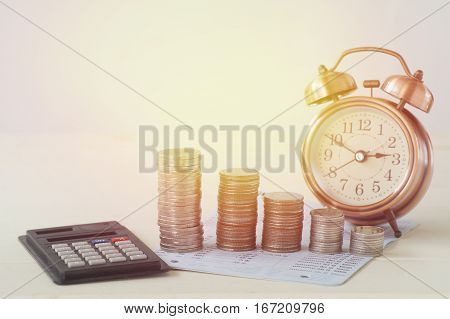 pile of money coins on book bank with clock calulator for business background