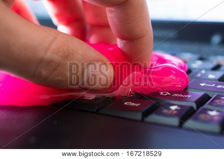 Keyboard cleaning gel in work. Hand and pink gel.