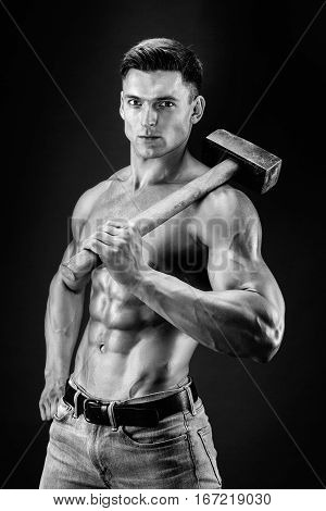 Muscular man with naked torso holding big hammer. Isolated on dark grey background