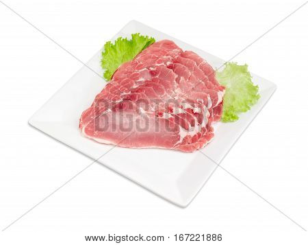 Sliced fresh chilled pork loin with lettuce leaves on a square white dish on a light background