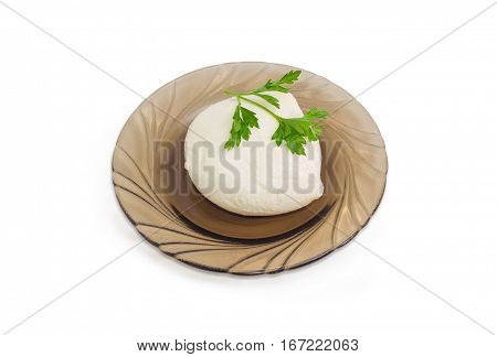 Piece of fresh mozzarella cheese with twig of parsley on the glass saucer on a light background