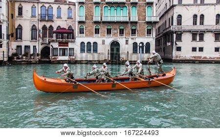 VeniceItaly- February 19 2012: A red boat with a group of funny disguised people sailing on the Grand Canal in a boats parade during the Carnival days.