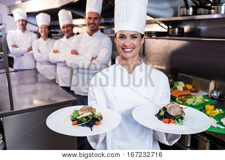 Team of chefs in the kitchen with one presenting dishes