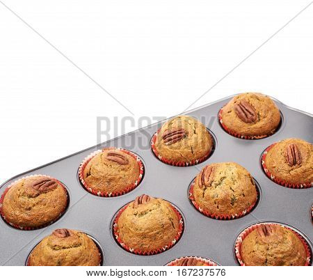 Muffin pan tray full of freshly baked pekan nut cupcakes isolated over the white background, close-up crop fragment