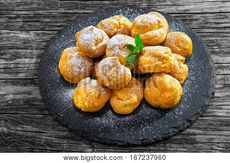 Delicious Profiteroles Filled With Cream On Slate Plate