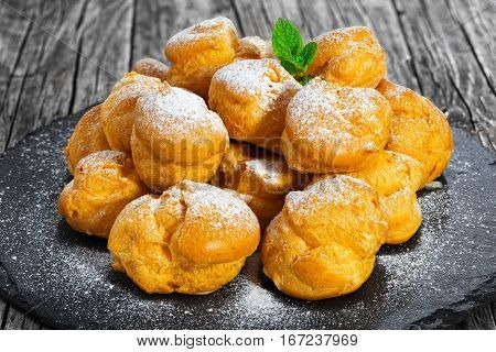 Delicious Profiteroles Filled With Cream On Slate Plate