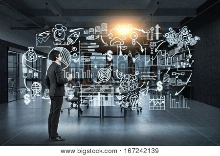 Side view of a businessman with a paper cup of coffee standing near a glassboard with a start up sketch drawn on it. Toned image