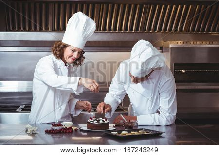 Chefs decorating a cake in a restaurant