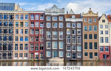 Colorful Houses And Boat At The Damrak In Amsterdam