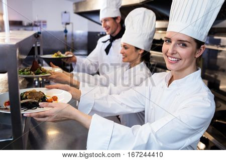 Chefs handing dinner plates through order station in the kitchen