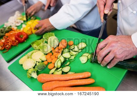 Close-up of chefs chopping vegetables on chopping board in the kitchen