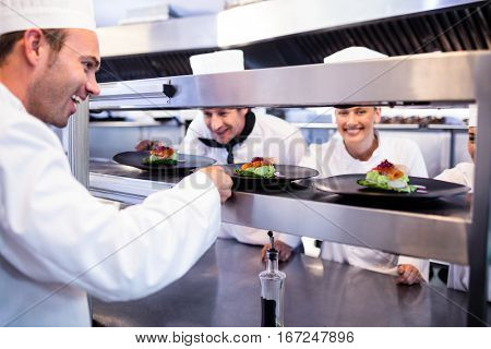 Chef handing appetizer plate through order station in the commercial kitchen