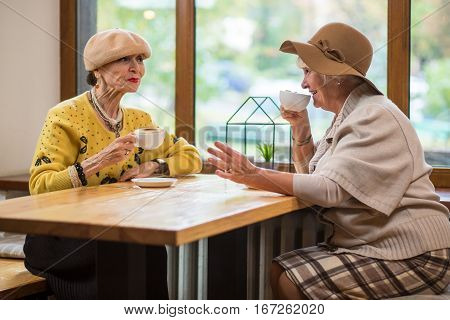 Senior women drinking coffee. Lady at the table smiling. Friendship and time.