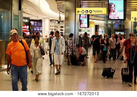 London, UK, 03 Jul. 2009: Passengers in Heathrow Airport. Toilet direction banner and various Ad banners.