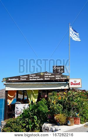 ELOUNDA, CRETE - SEPTEMBER 17, 2016 - Greek taverna along the waterfront with a flag on the roof Elounda Crete Greece Europe, September 17, 2016.