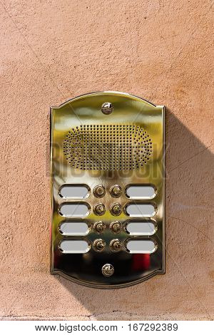 Detail of a golden intercom with eight doorbell buttons with empty copy space on a wall. Italy