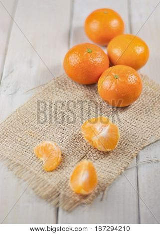 Group of tangerines in the background and peeled mandarin in the foreground.