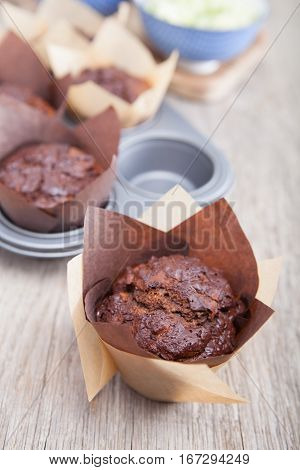 Flourless chocolate courgette muffins in a muffin tin on a wooden table