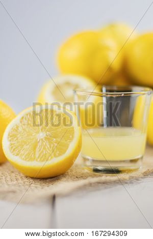 A glass of squeezed lemon juice and lemons around.